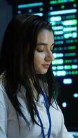 Vertical Computer scientist overseeing data center, making improvements and updates to ensure system can handle networking tasks. Close up of woman in server room tracking network traffic, camera A video