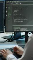 Vertical Software developer in data center ensuring system can handle networking tasks. IT professional in server room tracking network traffic with PC, making improvements, camera A video