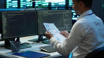 System administrator in data center maintaining accurate paperwork of hardware, generating reports. IT expert in high tech server farm doing workplace disaster recovery planning, camera A video