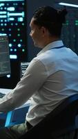 Vertical Data center system administrator responsible for installation of networking equipment solving tasks. IT employee at work doing maintenance on server room hardware, camera A video
