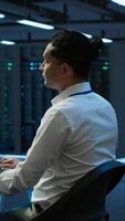 Vertical Developer and coworker overseeing data center, making improvements and updates to ensure system can handle networking tasks. Teamworking colleagues in server room tracking network traffic, camera A video