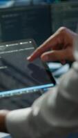 Vertical Programmer using device in data center, managing servers, operating systems. Close up of specialist in server hub using tablet to ensure networks are secure and functioning properly, camera A video