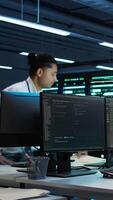 Vertical Team of researchers in data center monitoring security threats using PC, implementing cybersecurity measures. Teamworking colleagues ensuring compliance with regulations, camera B video