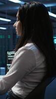 Vertical Software developer in data center ensuring system can handle networking tasks. IT professional in server room tracking network traffic with PC, making improvements, camera B video