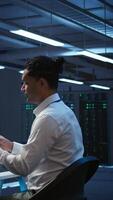 Vertical System administrator in data center maintaining accurate paperwork of hardware, generating reports. IT expert in high tech server farm doing workplace disaster recovery planning, camera B video