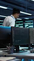 Vertical Computer scientists in data center managing and maintaining databases, ensuring data integrity and security. IT staff members updating server room systems using, camera B video