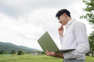 Modern Farmer Using Technology in Agriculture Field with Laptop for Efficient Farming Practices and Data Analysis photo