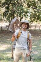 Young Man Enjoying a Hike in the Forest Holding a Large Leaf and Smiling on a Sunny Day photo