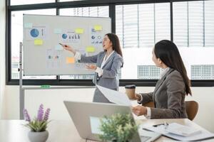 Businesswomen Discussing and Exchanging Ideas in a Modern Office Setting with Charts and Graphs photo