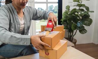 Young Woman Packing and Sealing Boxes for Online Sales in a Modern Home Office Environment photo