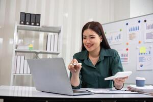 Young Accountant Analyzing Financial Documents on Laptop in Modern Office Setting with Charts and Graphs in Background photo