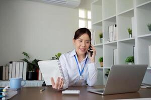 Professional Female Accountant Talking on the Phone While Working at Her Desk in a Modern Office Setting photo