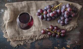 Grapes on a rustic burlap cloth with a glass of red wine photo