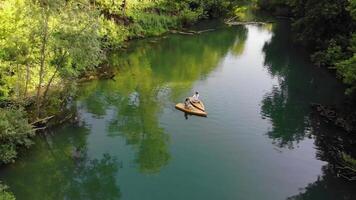 Two lovers are floating on the river in wooden rafts. Their boats are joined together in the shape of a heart, symbolizing their deep feelings for each other. Aerial footage. Top view video