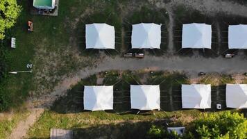 Top view of several large white tents standing in a row at the campsite. video