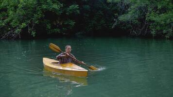 Young and focused traveler is attempting to reach the riverbank by using paddles while navigating a canoe down the river. video