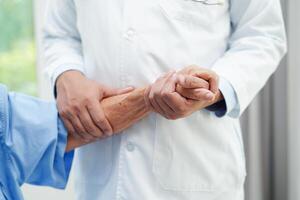 médico tomados de la mano paciente anciana asiática, ayuda y atención en el hospital. foto