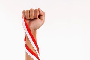 Man with strong arms and clenched fists holding red and white ribbons as a symbol of the Indonesian flag. Indonesian Independence day concept. photo