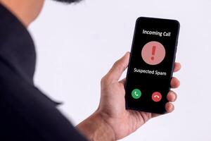 Hand holding a smartphone with incoming call from unknown caller on the screen. Spammer incoming call concept. photo