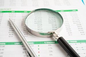Magnifying glass on spreadsheet and graph paper. Financial development, Banking Account, Statistic, Investment Analytic research data economy, Business. photo