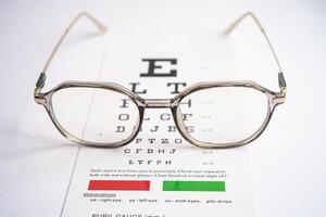 Glasses on eye testing exam chart to check eyesight accuracy of reading. photo