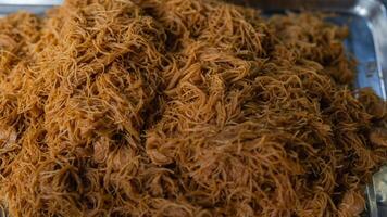 A pile of noodles is piled on top of each other. The noodles are brown and appear to be cooked photo