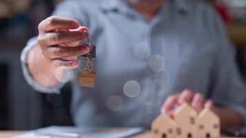 A man is holding a key in one hand, and a house keychain in the other. This scene hints that he is about to open a door, likely to a new home, symbolizing new beginnings and possibilities. photo