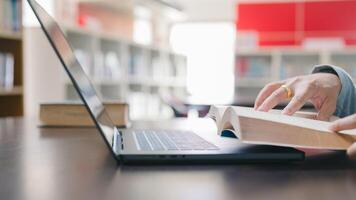 Man read book concept. A person is using a laptop and a book on a table. The person is likely studying or working on a project. education, school, learning, student photo