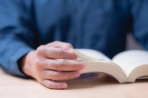 Reading and learning book concept. A man is reading a book with his hand on the page. The book is open to a page with a picture of a person photo