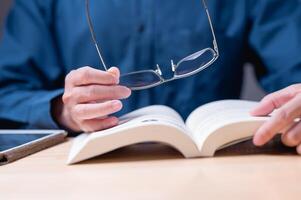 Reading book concept. A man is reading a law book with his glasses on. He is wearing a blue shirt. The book is open to a page with a picture of a person photo
