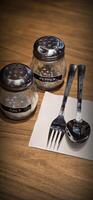 simple American diner style salt and pepper glass shakers sits on table with wooden background, selective focus background, good for recipe book or web blog photo