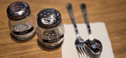 simple American diner style salt and pepper glass shakers sits on table with wooden background, selective focus background, good for recipe book or web blog photo