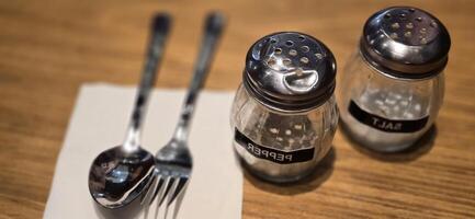 simple American diner style salt and pepper glass shakers sits on table with wooden background, selective focus background, good for recipe book or web blog photo
