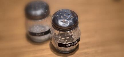 simple American diner style salt and pepper glass shakers sits on table with wooden background, selective focus background, good for recipe book or web blog photo