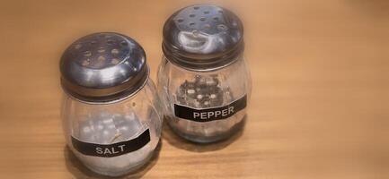 simple American diner style salt and pepper glass shakers sits on table with wooden background, selective focus background, good for recipe book or web blog photo