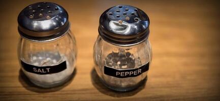 simple American diner style salt and pepper glass shakers sits on table with wooden background, selective focus background, good for recipe book or web blog photo