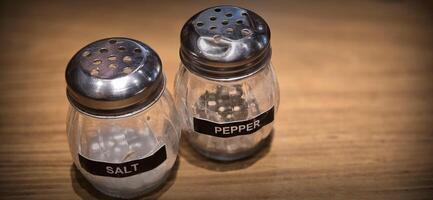 simple American diner style salt and pepper glass shakers sits on table with wooden background, selective focus background, good for recipe book or web blog photo