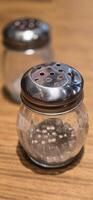 simple American diner style salt and pepper glass shakers sits on table with wooden background, selective focus background, good for recipe book or web blog photo