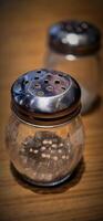 simple American diner style salt and pepper glass shakers sits on table with wooden background, selective focus background, good for recipe book or web blog photo