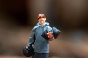 Miniature people, A man lifting dumbbells is set against a textured background photo