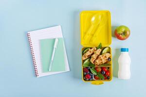 Kids lunch box with zucchini waffles, cucumber, cherry tomatoes and blueberries. Back to school breakfast background. Copy space. Top view, flat lay photo