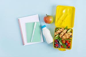 Kids lunch box with zucchini waffles, cucumber, cherry tomatoes and blueberries. Back to school breakfast background. Copy space. Top view, flat lay photo