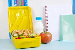Kids lunch box with zucchini waffles, cucumber, cherry tomatoes and blueberries. Back to school breakfast background. Copy space. Top view, flat lay photo