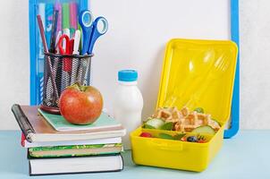 Kids lunch box with zucchini waffles, cucumber, cherry tomatoes and blueberries. Back to school breakfast background. Copy space. Top view, flat lay photo