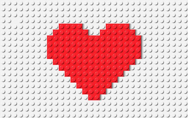 Simple red heart composed of many plastic building toy blocks. Close-up of a colorful bricks. Abstract background illustration