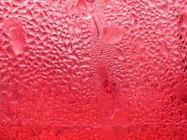 Drops of ice on a red cold drink glass photo