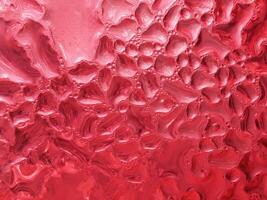Drops of ice on a red cold drink glass photo