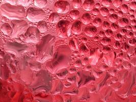 Drops of ice on a red cold drink glass photo