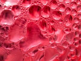 Drops of ice on a red cold drink glass photo