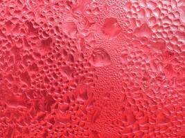 Drops of ice on a red cold drink glass photo